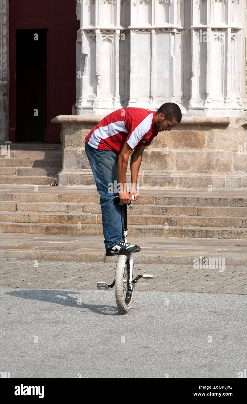 Man balancing on a unicycle in front of the Cathedral of St. Peter and St. Paul, Nantes Stock Photo