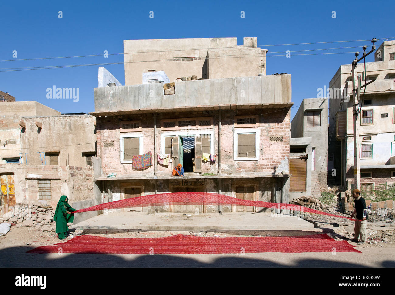 Man and woman drying a red silk fabric. Nagaur. Rajasthan. India Stock Photo