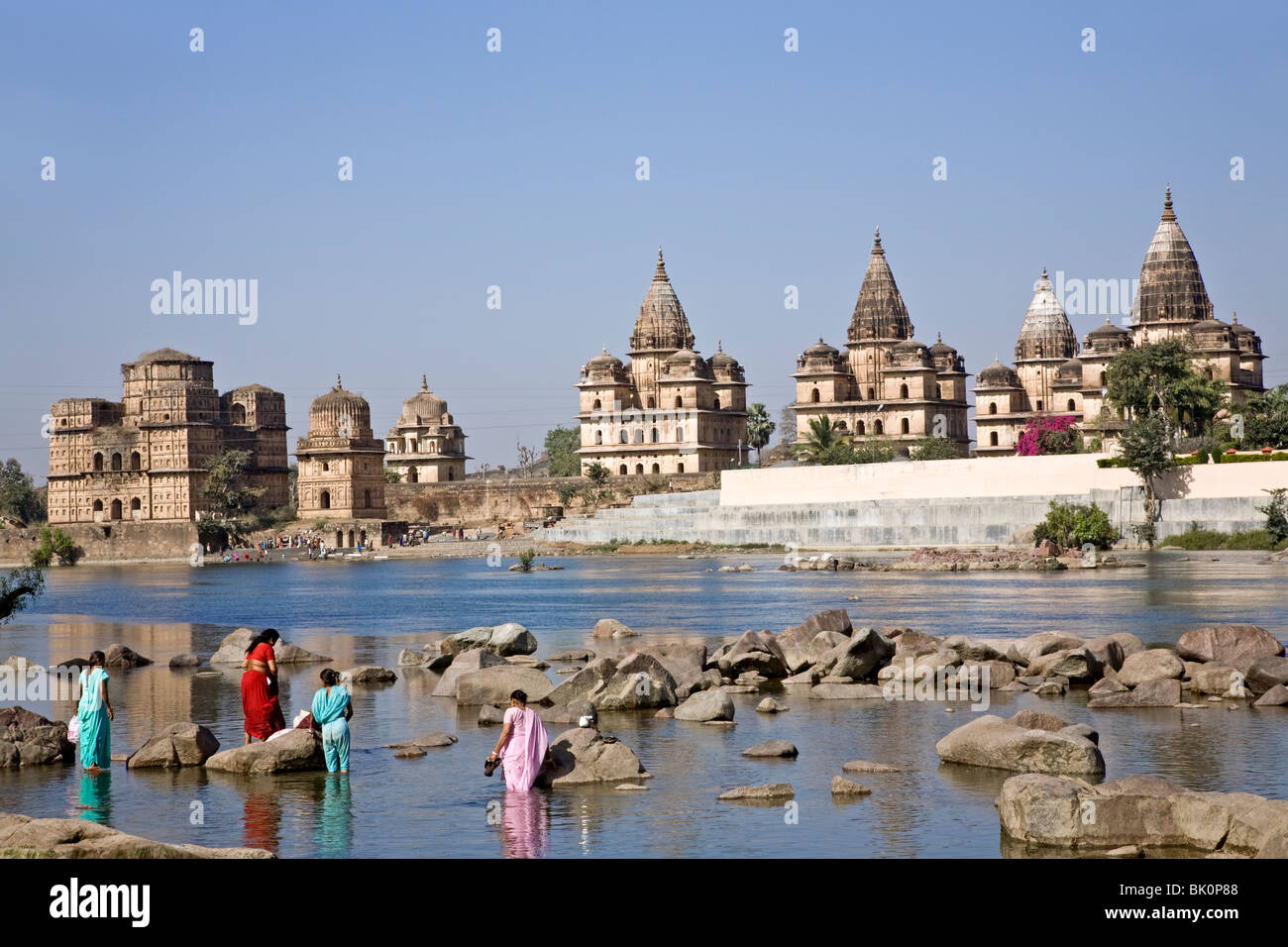 Indian women bathing in the Betwa river. On the background the Royal chhatris (cenotaphs) Orchha. Madhya Pradesh. India Stock Photo