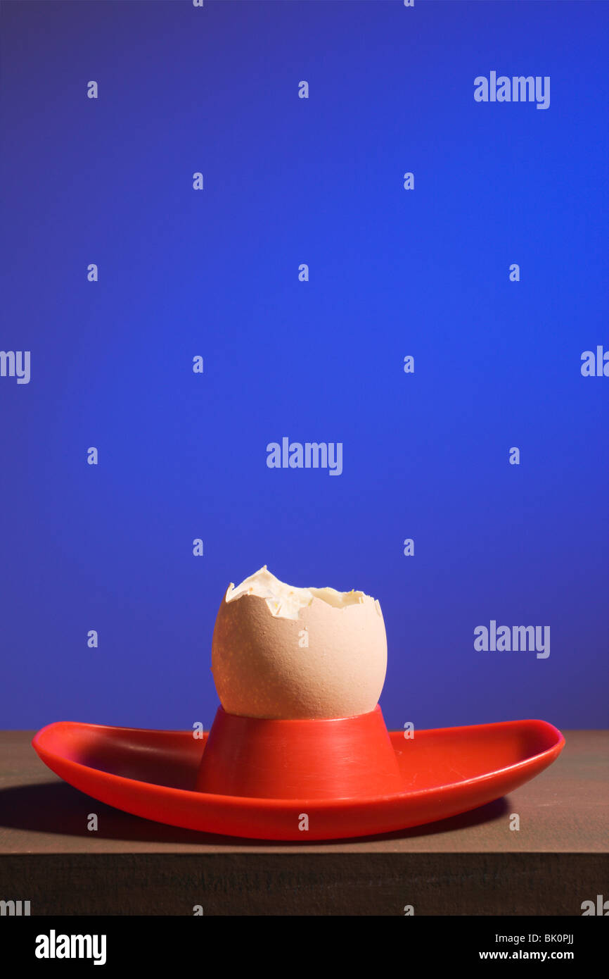 An eaten egg in a red eggcup on blue. Stock Photo