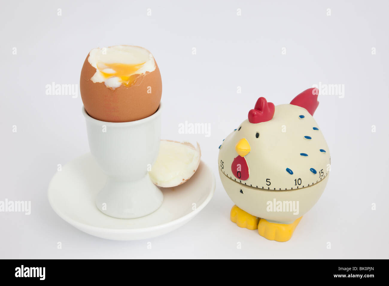 Chicken egg timer with an open soft boiled egg in an egg cup on a white background Stock Photo