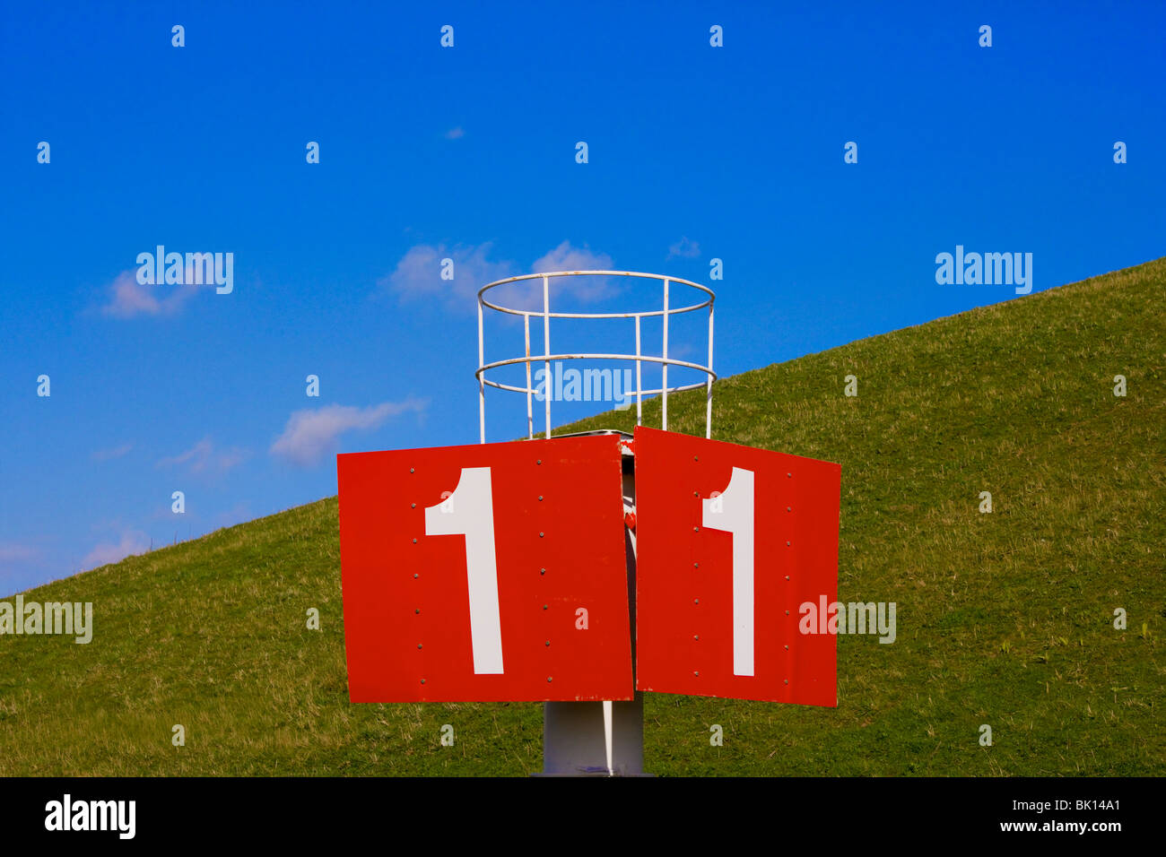 A big red sign with the number no 1, one, in front of a dike, dyke, levee, in Holland. Landmark beacon, nautical sign. Stock Photo