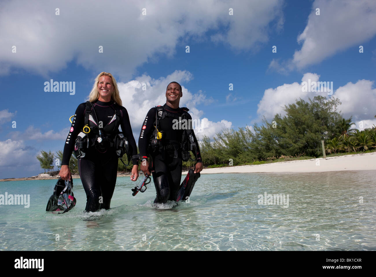 Scuba divers wading into water in full gear. Stock Photo