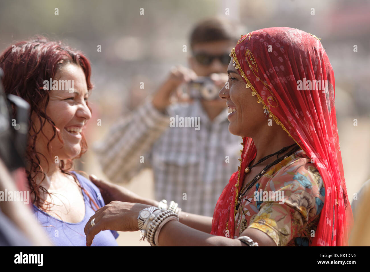 Indian and a foreigner lady greeting each other at Pushkar camel race, Rajasthan India. Stock Photo
