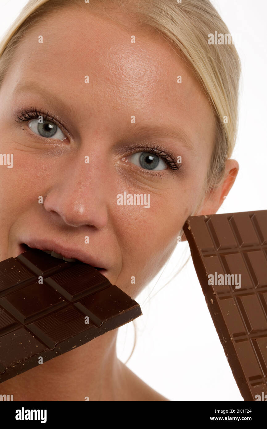 young beautyful caucasian woman eating a chocolate bar and looking at the camera Stock Photo