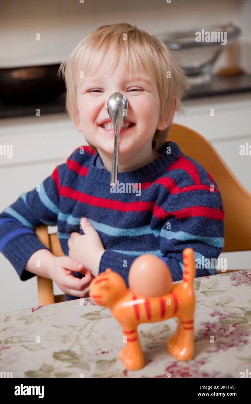 Boy balancing a spoon on his noise before eating a boiled egg Stock Photo