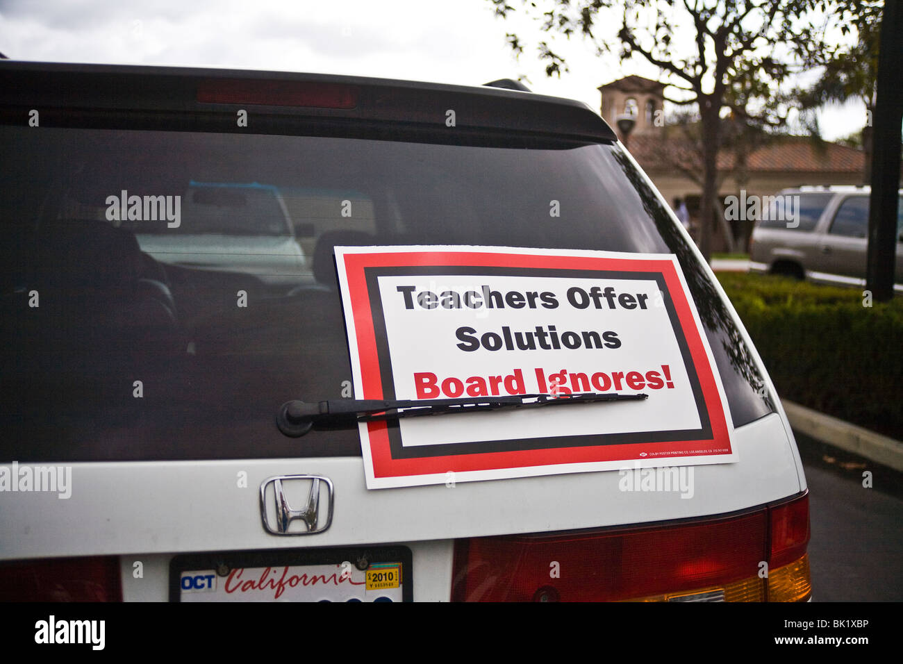 Vehicle in school parking lot displays poster showing teacher dissatisfaction with school board policy. Stock Photo