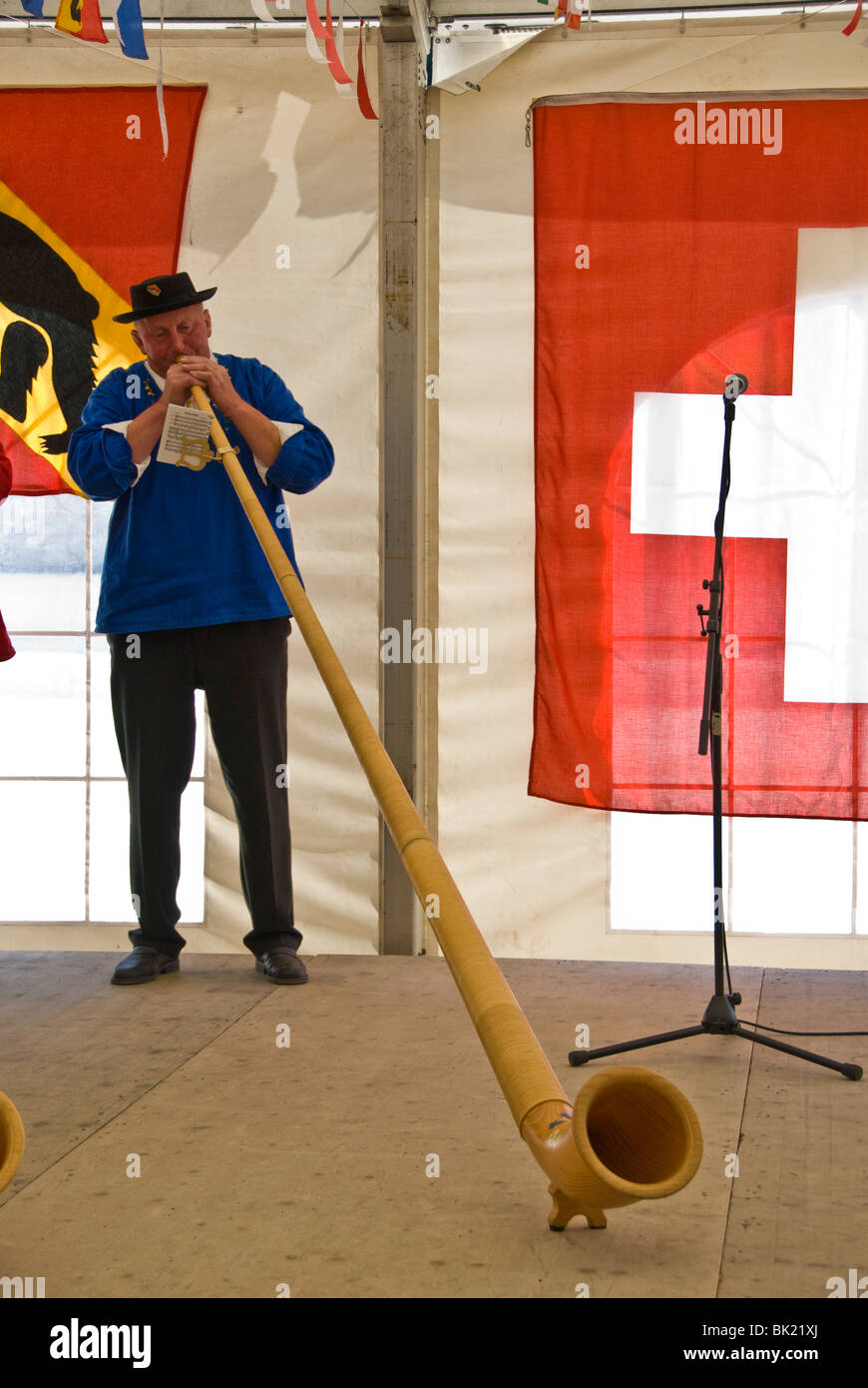 Man playing alphorn or alpenhorn or alpine horn at the Wengen Cheese Festival in Switzerland, the alphorn is a is a labrophone Stock Photo