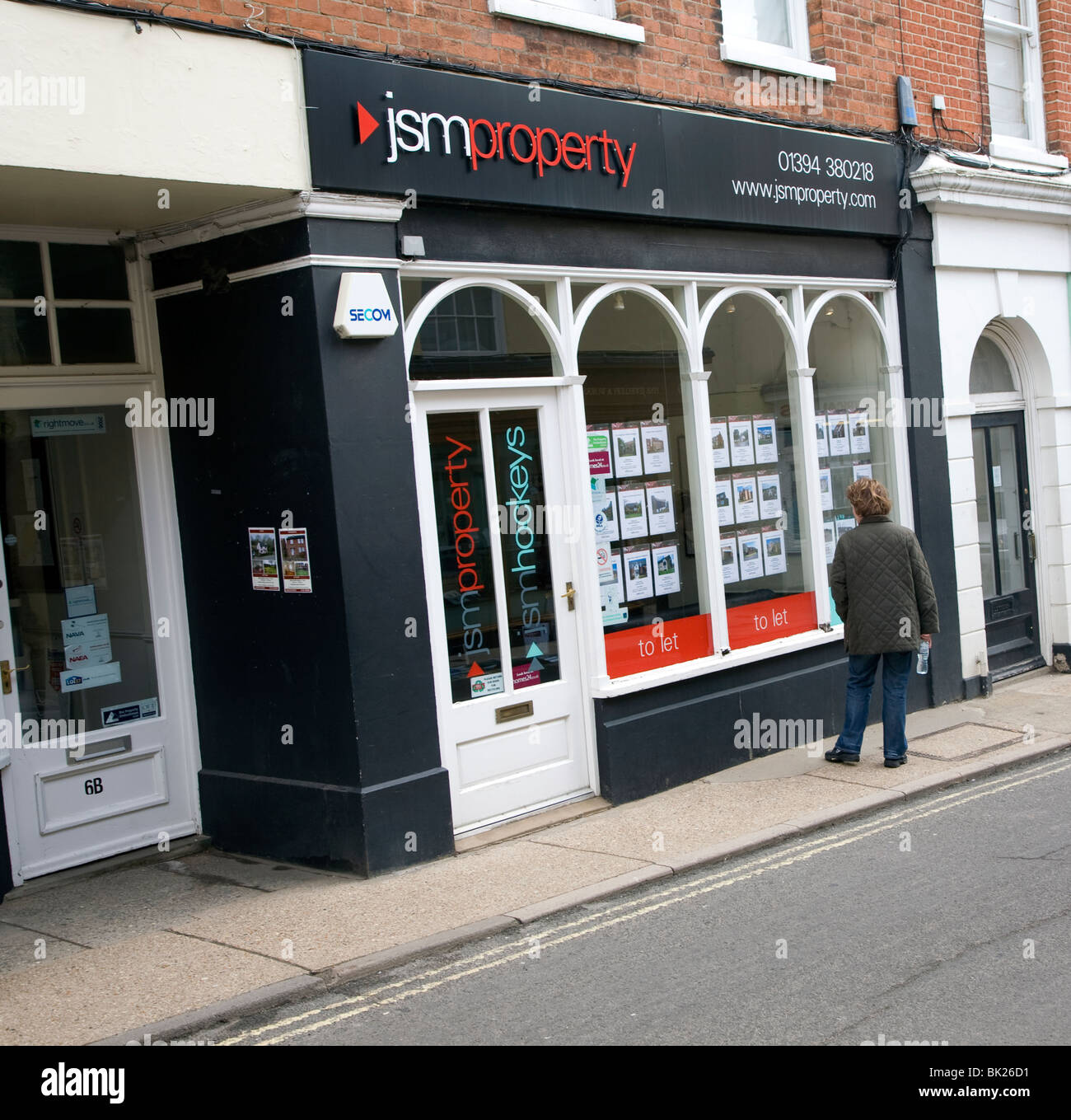 Woman looking in JSM property estate agent shop window Woodbridge