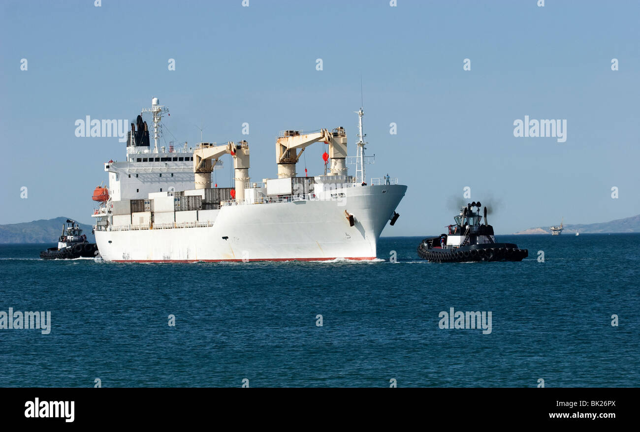 Tug boats guiding a container ship Stock Photo