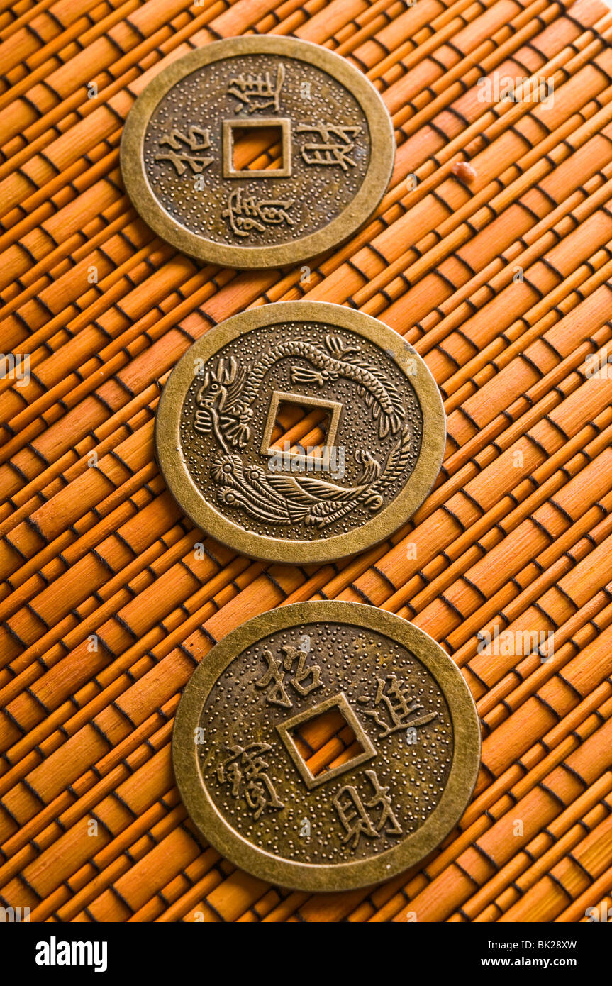 three ancient Chinese coins for i ching divination on a bamboo surface Stock Photo