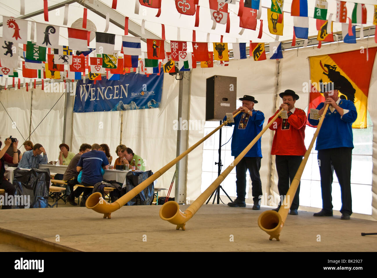 Men playing alphorn or alpenhorn or alpine horn at the Wengen Cheese Festival in Switzerland, the alphorn is a is a labrophone Stock Photo