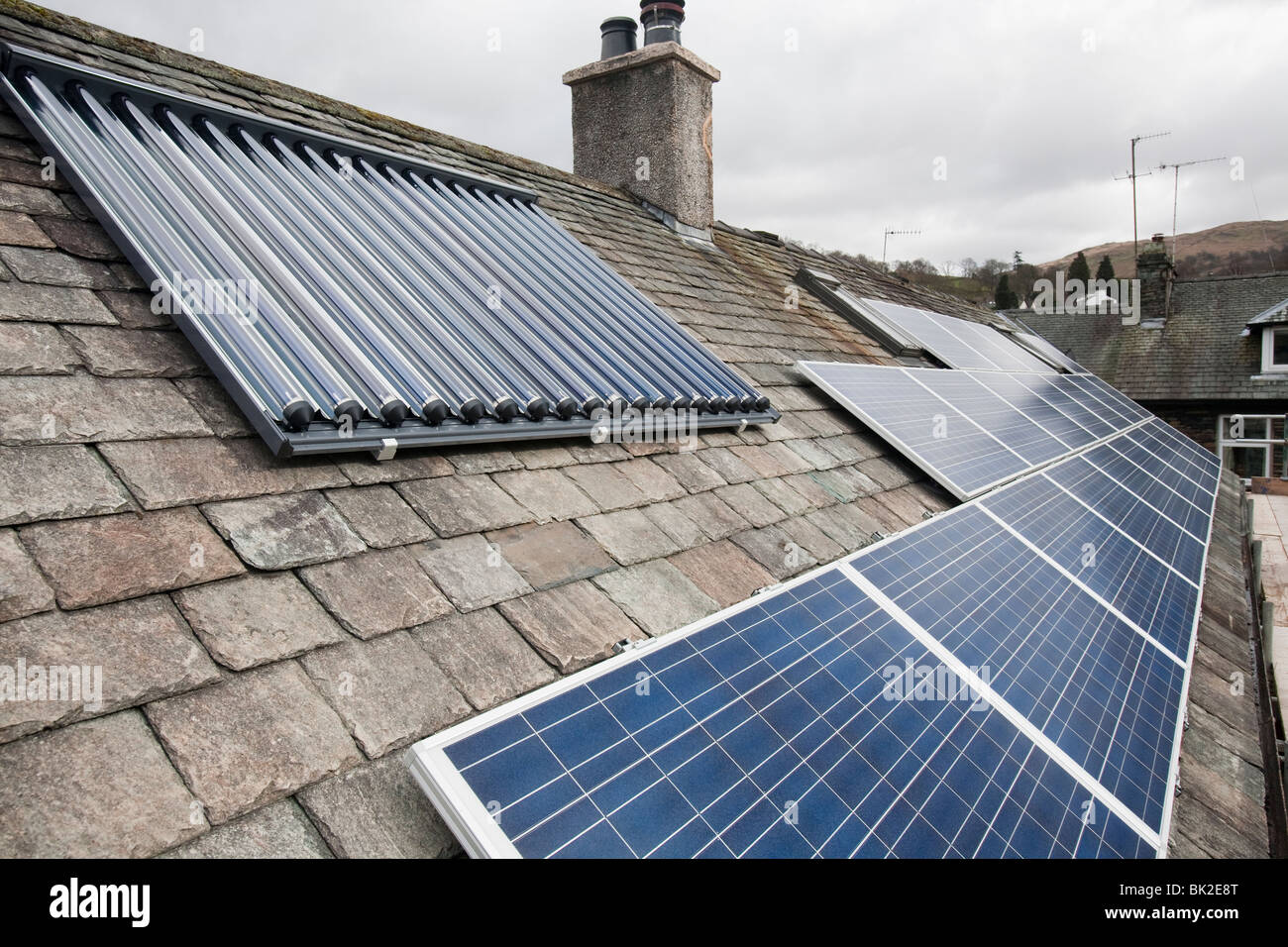 Solar voltaic electricity generating panels and solar hot water panels on a house roof in Ambleside, Cumbria, UK. Stock Photo