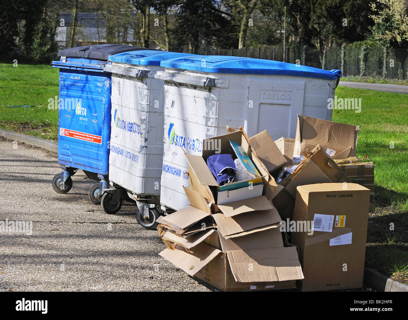 Line of large commercial wheelie bins with abandoned pile of cardboard - Reading, Berkshire, England, UK Stock Photo