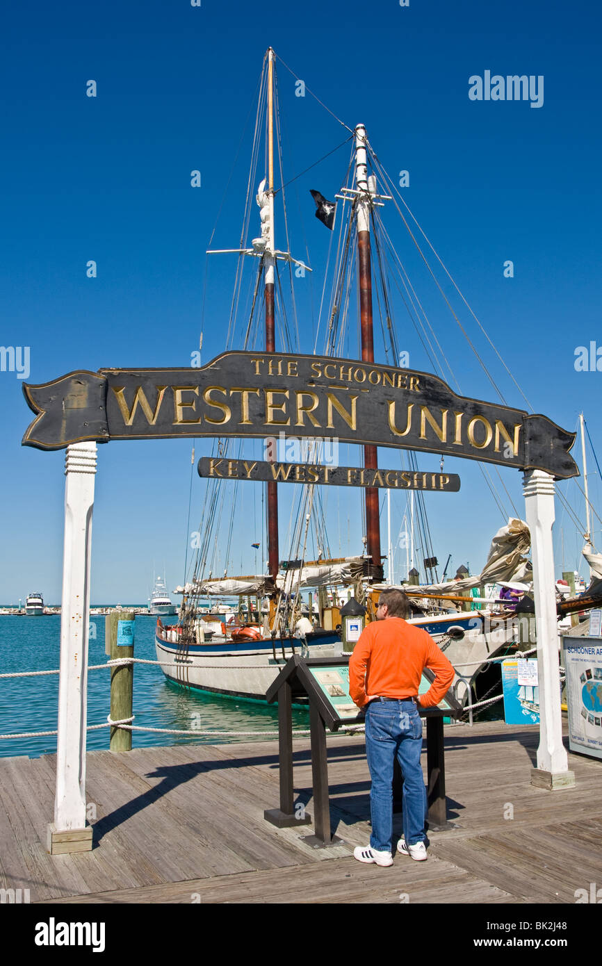 The Schooner Western Union sign and tall ship at the marina, Florida, USA. Tourist reading information board. Stock Photo