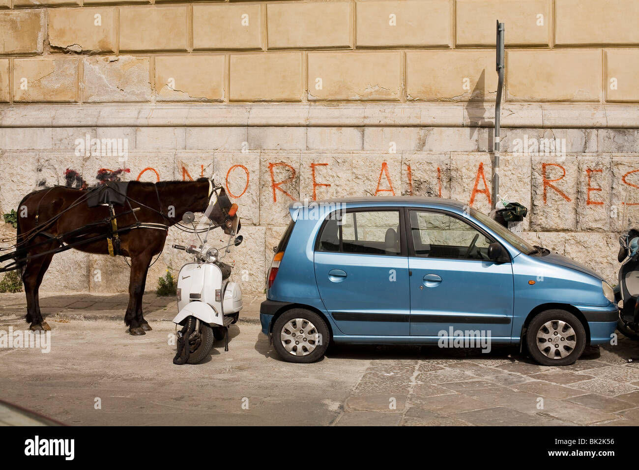 modes of transport: car, motor-scooter, donkey against a wall with graffiti Stock Photo