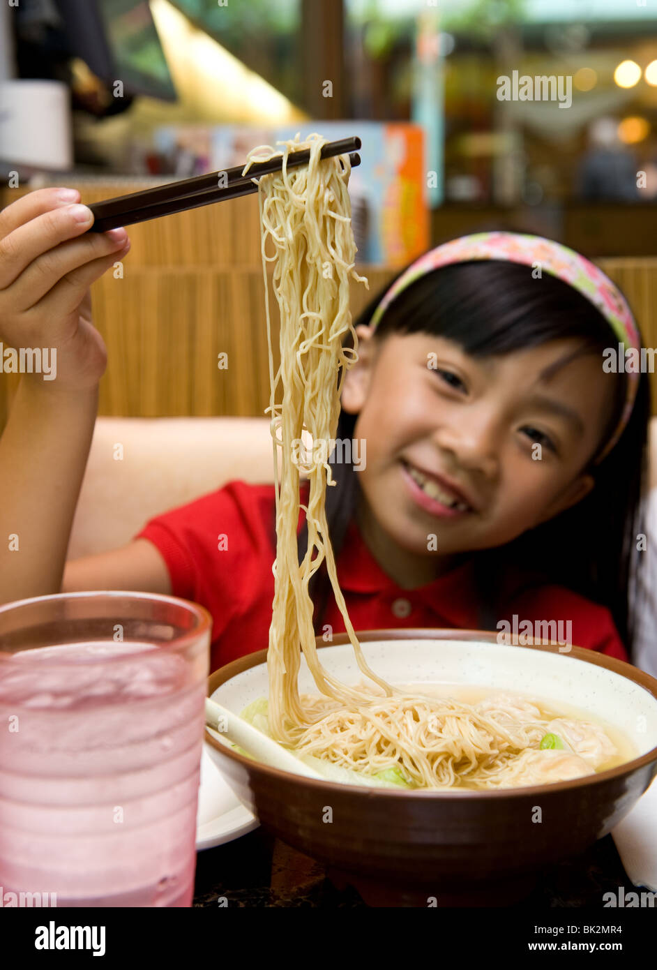 Chinese girl eating shrimp wonton and noodle soup with chopsticks at Chi Cafe in Chicago, IL Stock Photo