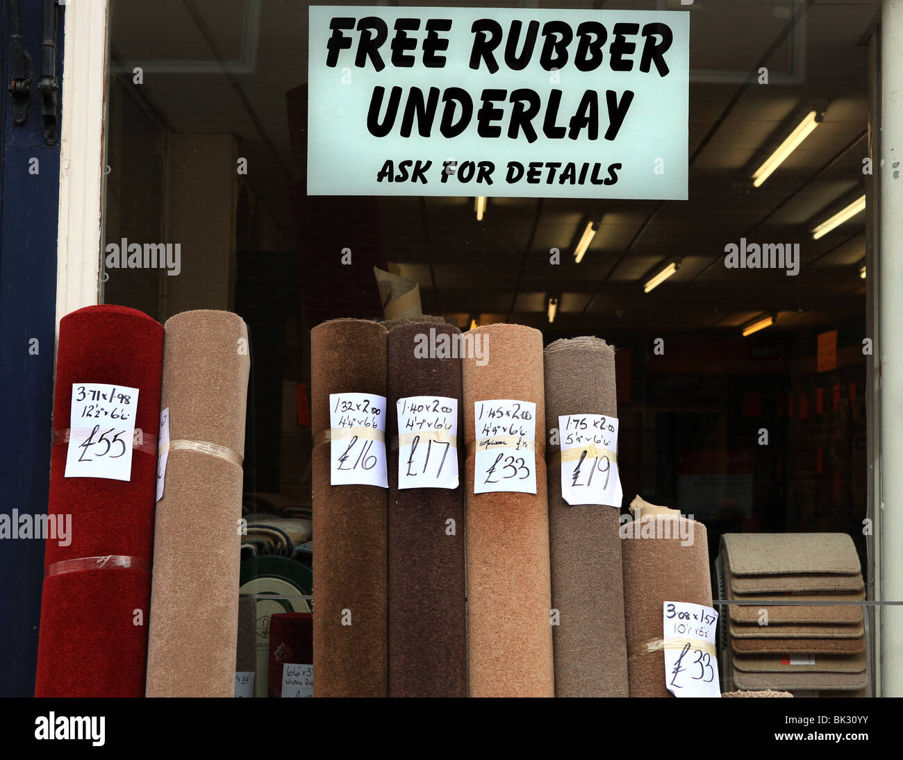 rolls of carpet outside a UK carpet shop with a sign advertising free