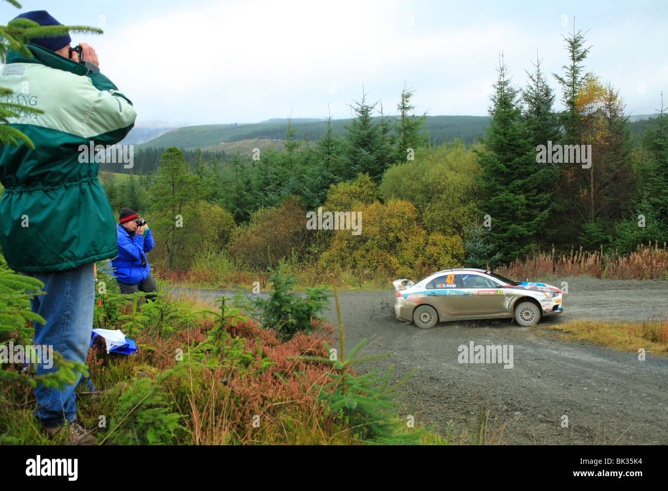 Spectators photographing a competitor in the WRC special stage held in the Hafren Forest, near Llanidloes, Powys, Wales. Stock Photo