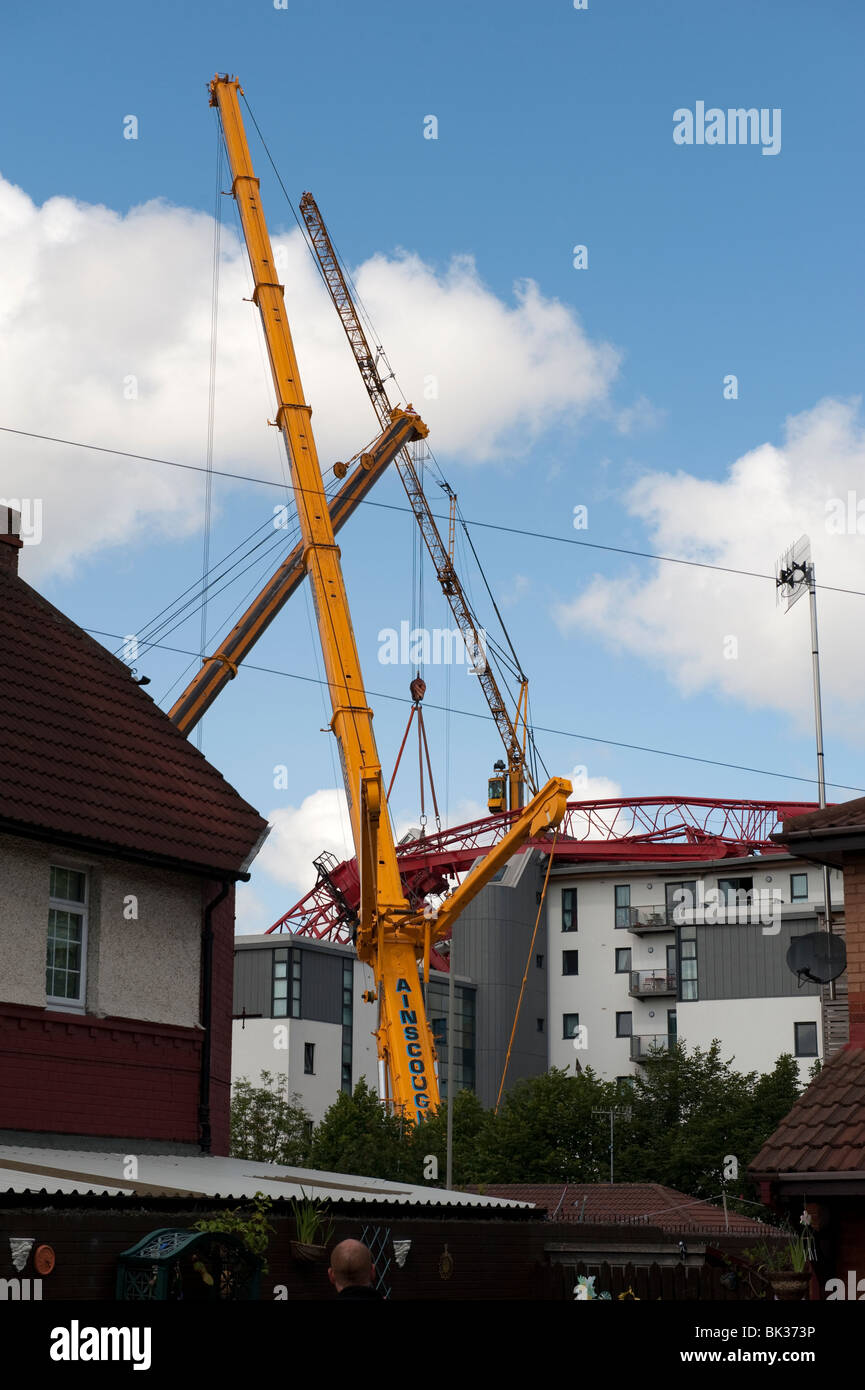 Tower crane collapsed fallen onto roof of apartment block being lifted off by another crane Stock Photo