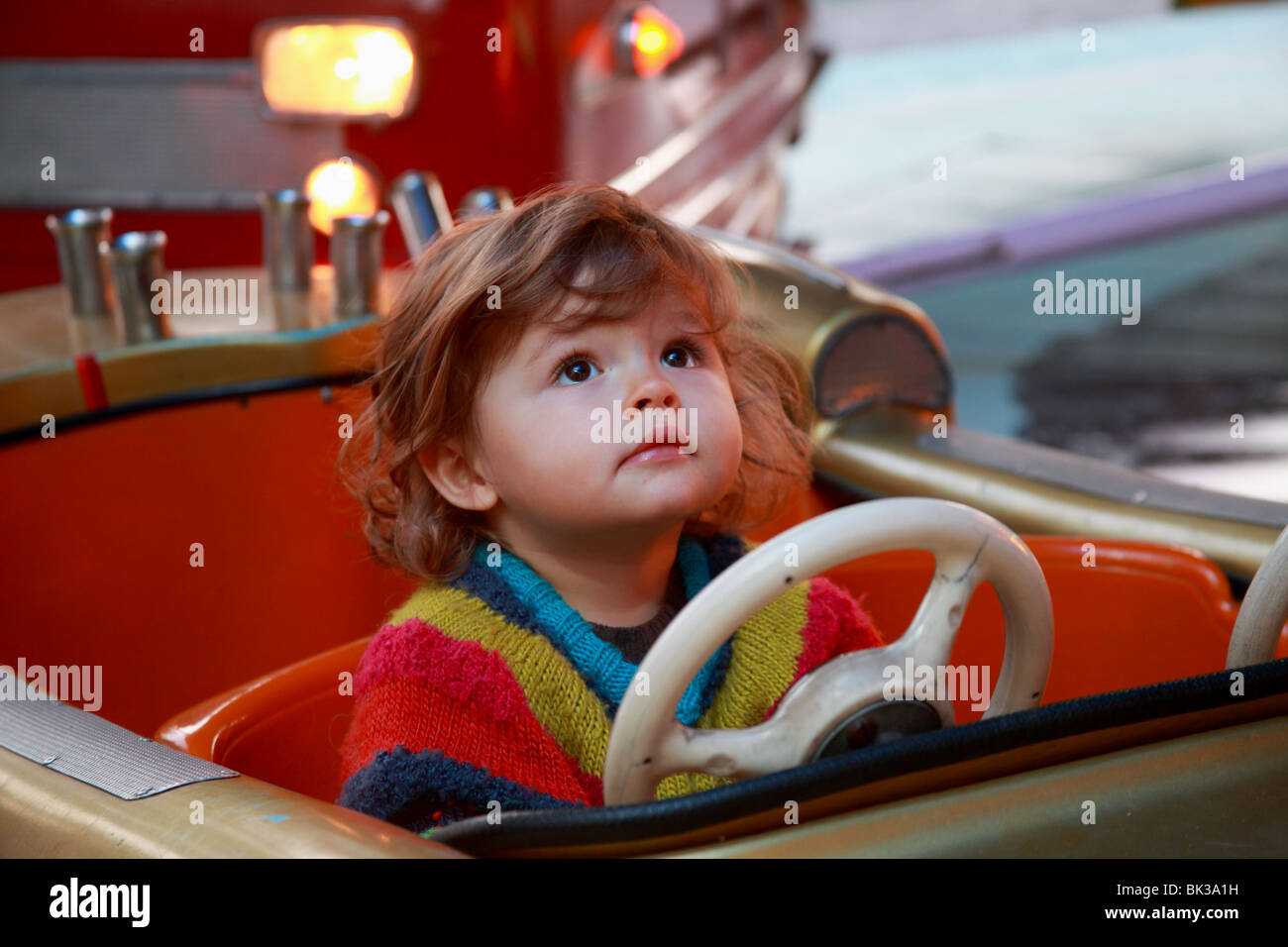 22 months old girl inside a fire car merry-go-round in motion Stock Photo