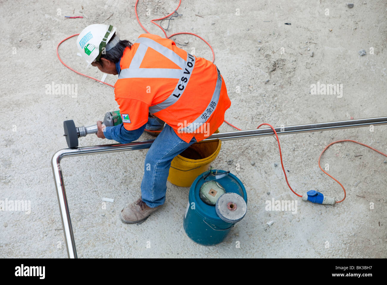 Steel Poll Work A workman on a building site in Hong Kong, China, polishing a steel ...