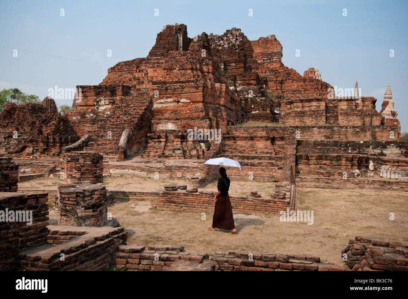 Woman visitor with umbrella at Wat Mahathat Buddhist temple ruins, Ayutthaya, Thailand. Stock Photo