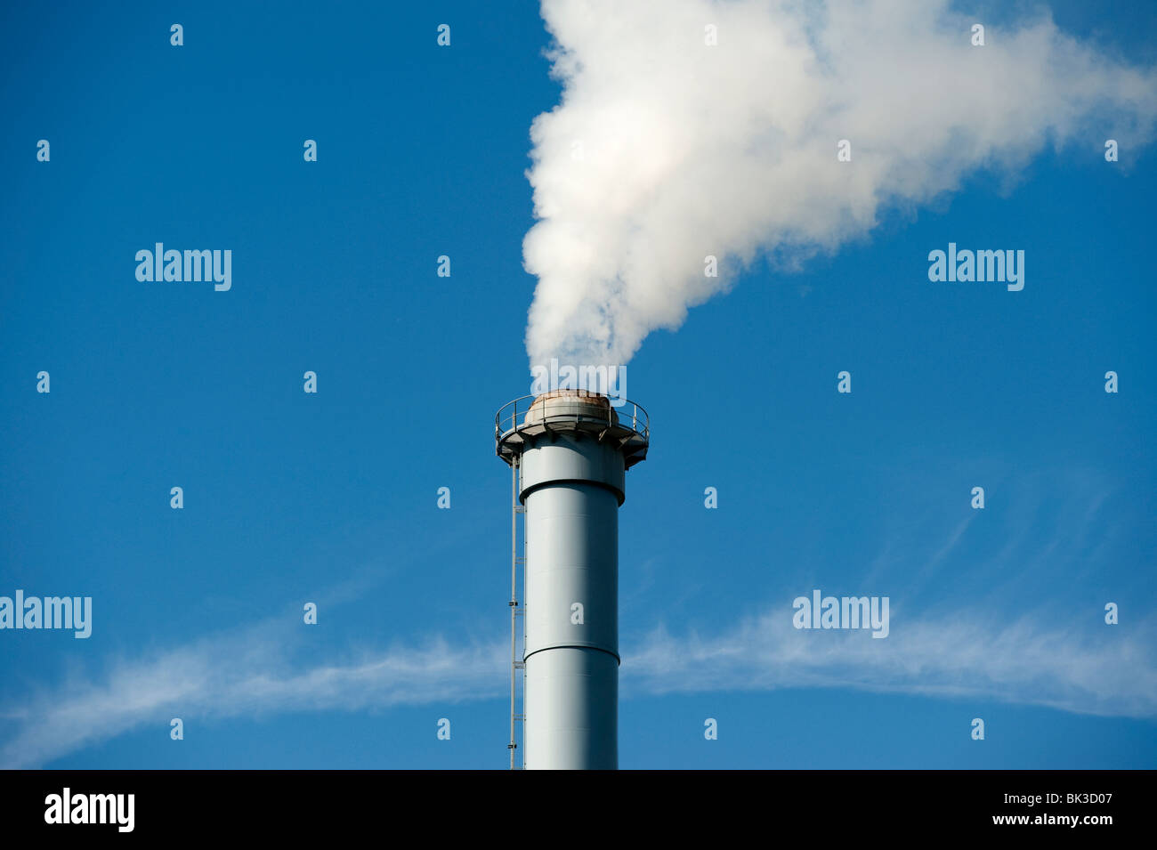 Factory chimney with smoke against blue sky Stock Photo - Alamy