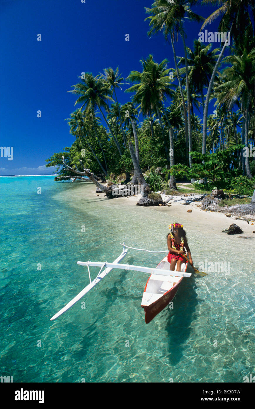 Woman paddling a traditional outrigger canoe in the lagoon of Raiatea