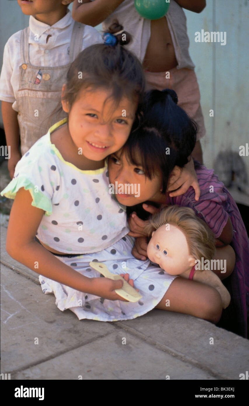 Two girls playing and combing the hair of a doll in the Amazon Region of Peru Stock Photo