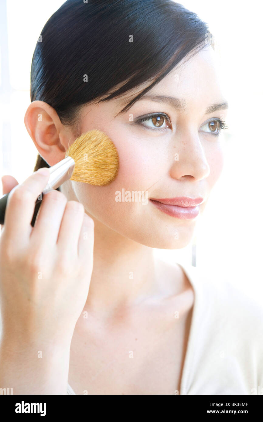 Asian woman applying blush Stock Photo Alamy