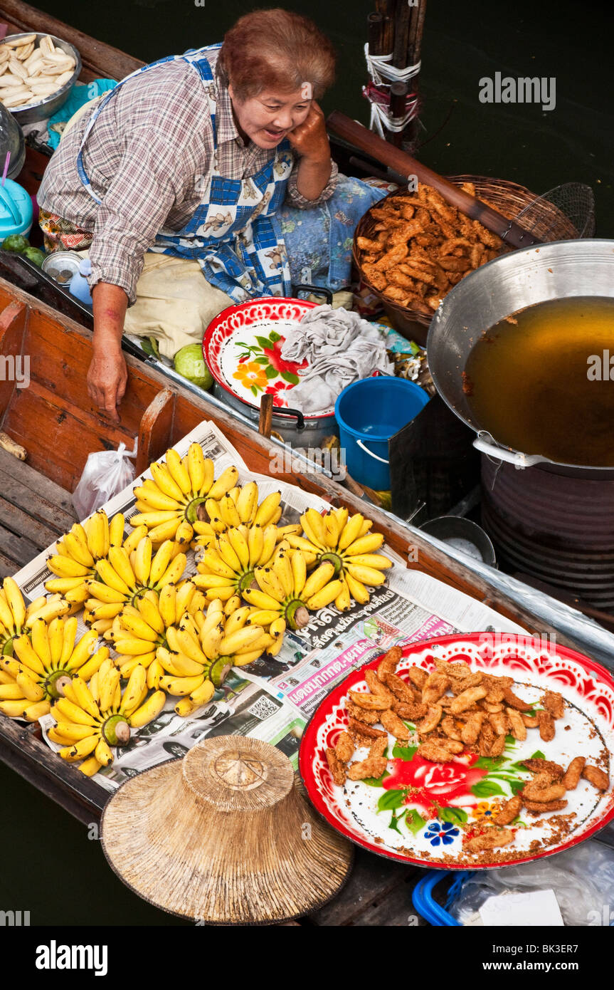 Woman selling food from boat at Damnoen Saduak Floating Market in Ratchaburi, Thailand. Stock Photo