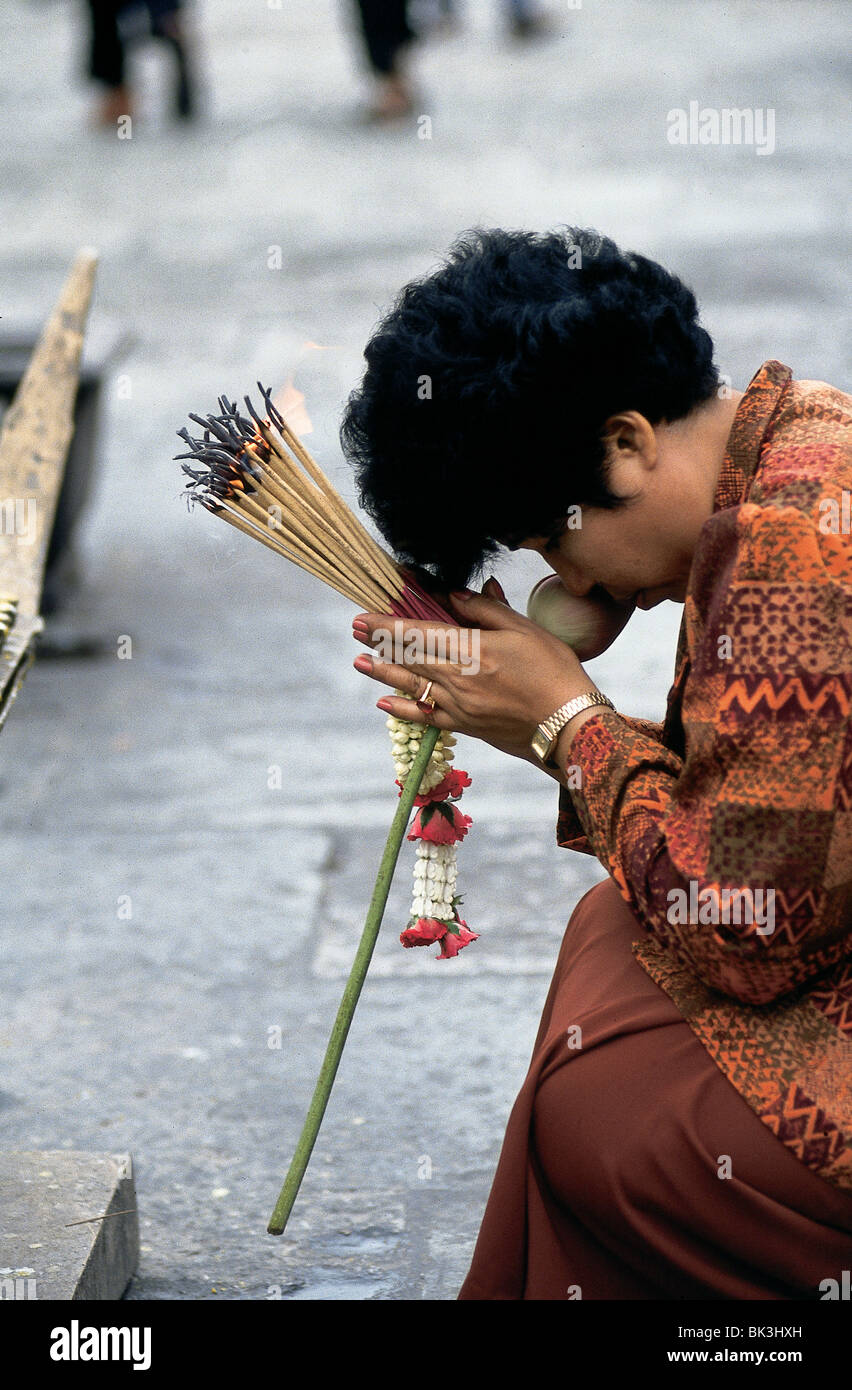 Woman praying, holding sticks of incense at Wat Arun, Thailand Stock Photo