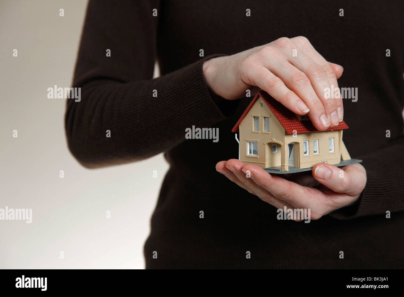 Hands holding a model house. Symbol: Property as a save investment Stock Photo