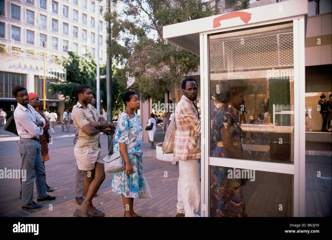 People waiting in line to make a phone call at a telephone booth in