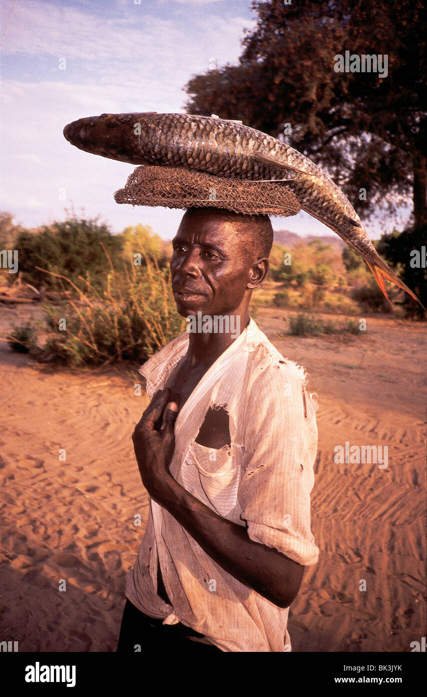 Man balancing a Tiger Fish on his head in Zimbabwe, Africa Stock Photo