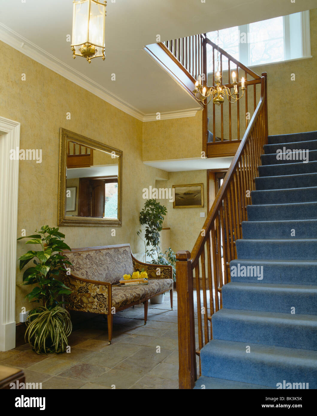 Blue carpet on staircase in traditional hall with cream wallpaper and