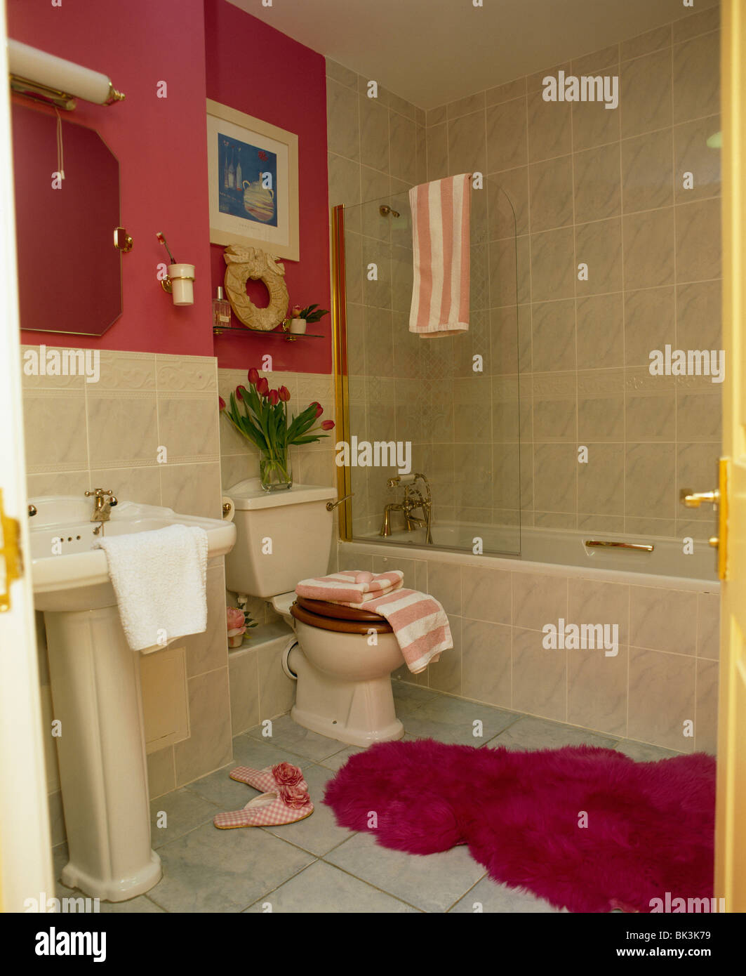 Fluffy Red Bathmat On Floor Of Red Bathroom With Cream Tiles Stock
