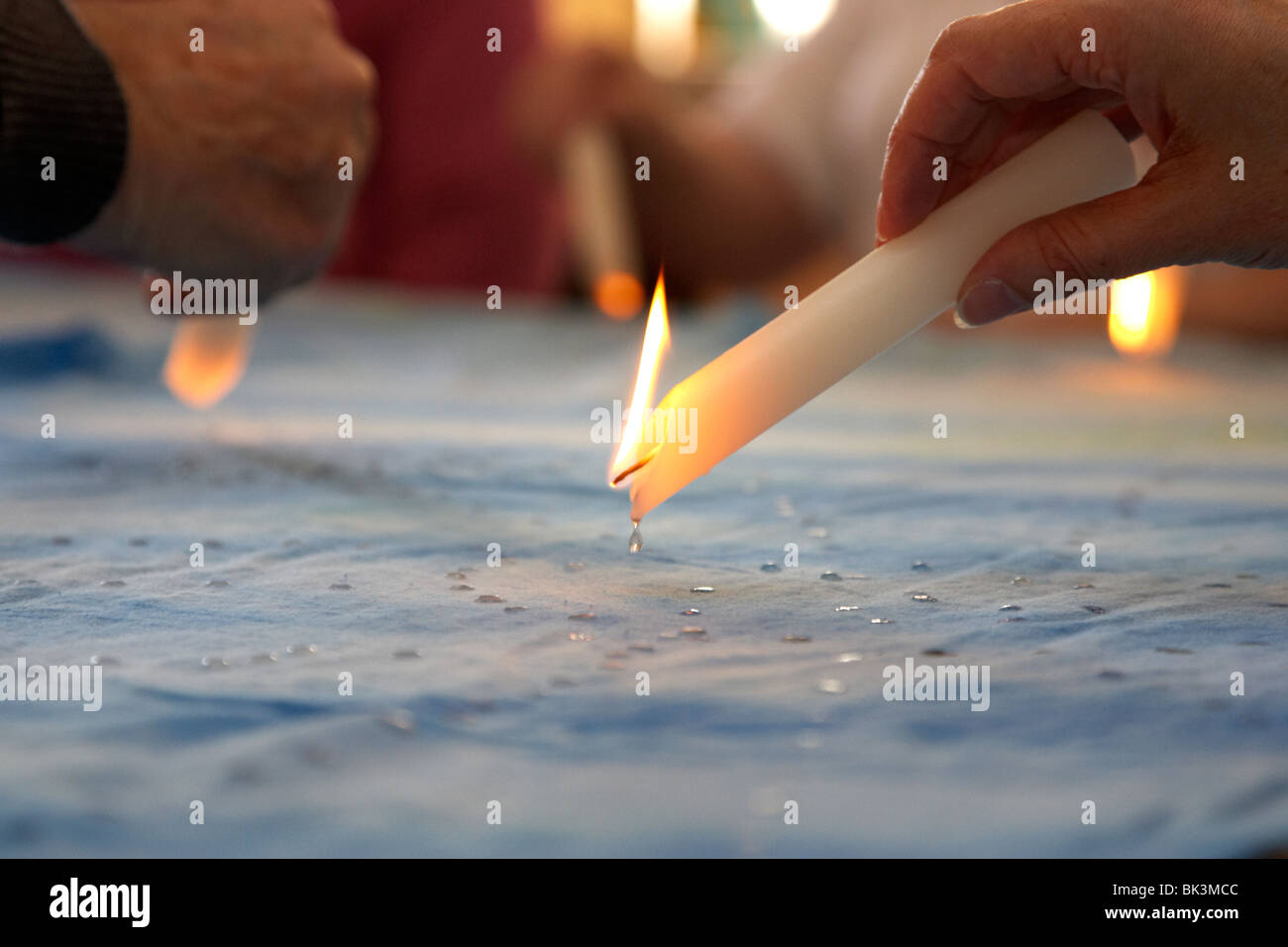 old people melting candles on fabric to create artwork in an old