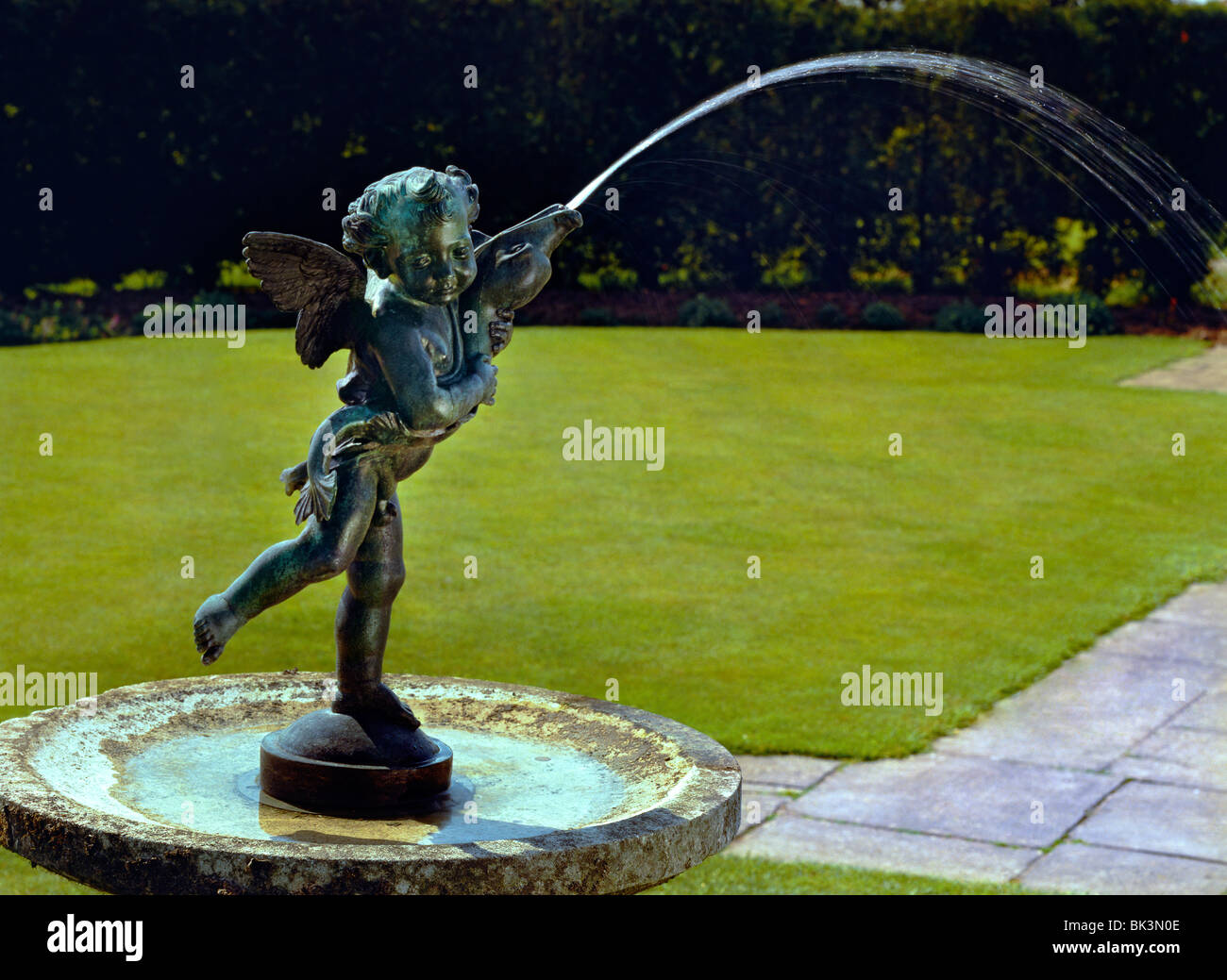 Cherub forming centerpiece of water fountain in formal garden Stock Photo