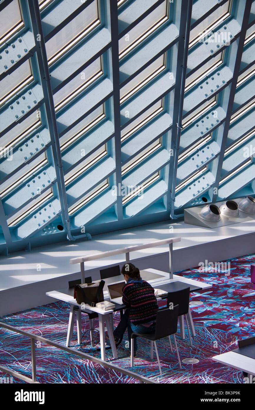 Woman At Desk With Natural Light From Glass Ceiling And Wall Of