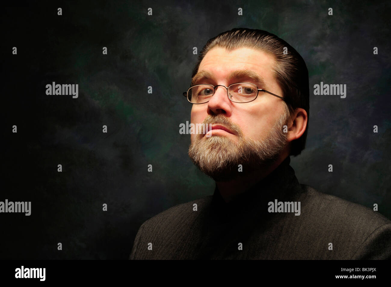 Orwellian character with glasses and beard against a dark background Stock Photo