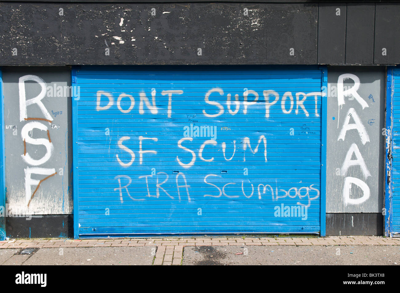 Graffiti on a shop shutter: 'Don't support SF scum. RIRA Scumbags' Stock Photo