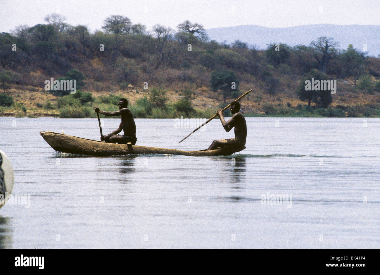 Two people paddling a dugout canoe on the Zambezi River ...