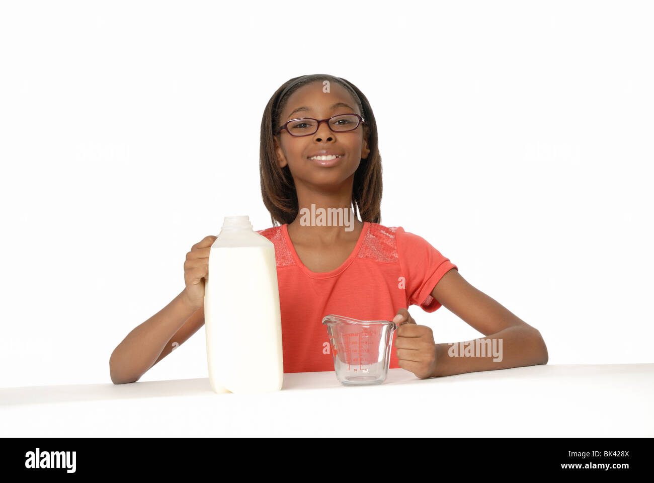 Ten year old girl with a half-gallon (1.89 L) container of milk and a measuring cup. Stock Photo
