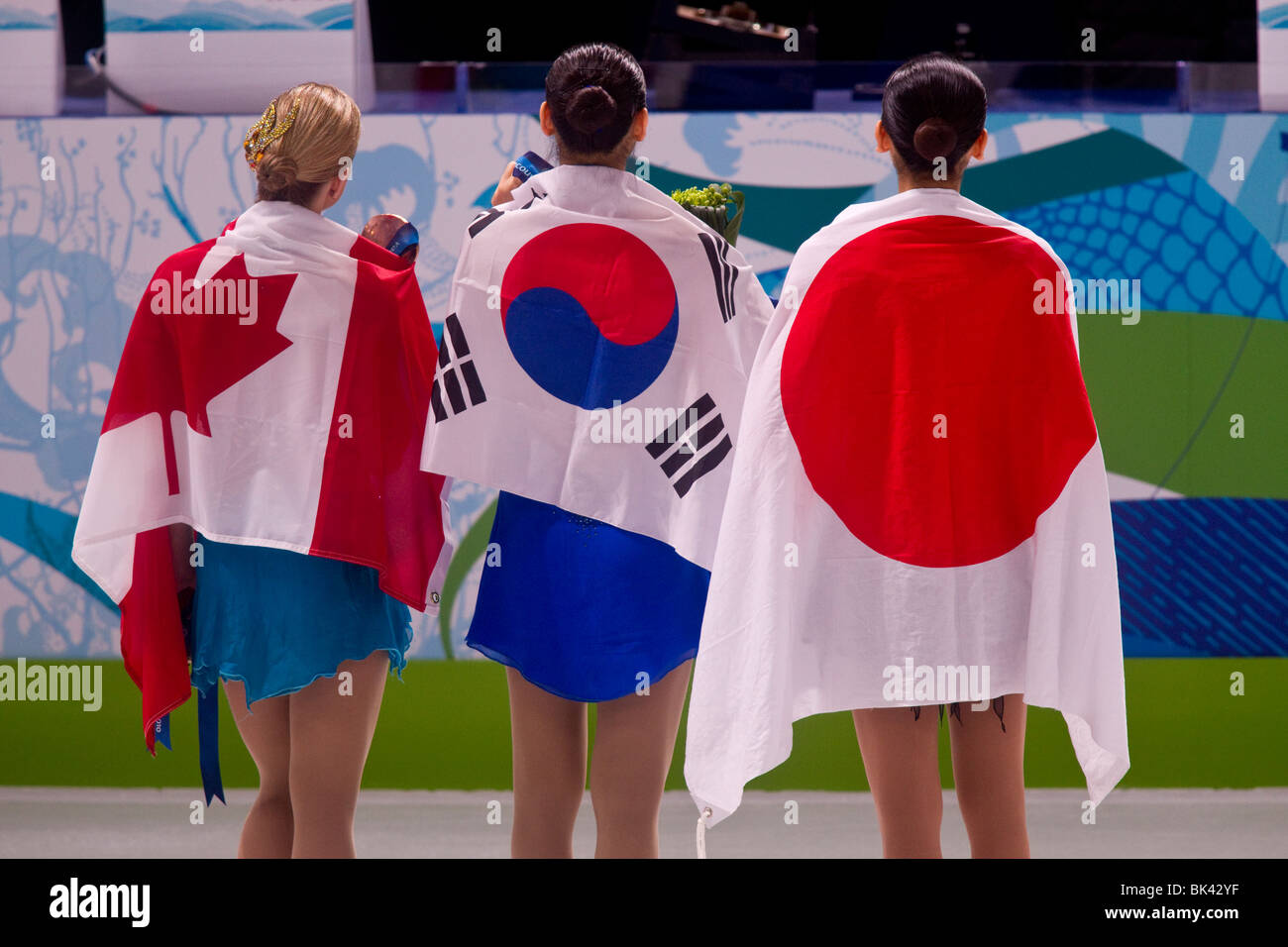 Kim Yu-Na (KOR), Mao Asada (JPN) and Joannie Rochette (CAN) wrapped in their country's flags after receiving their medals Stock Photo