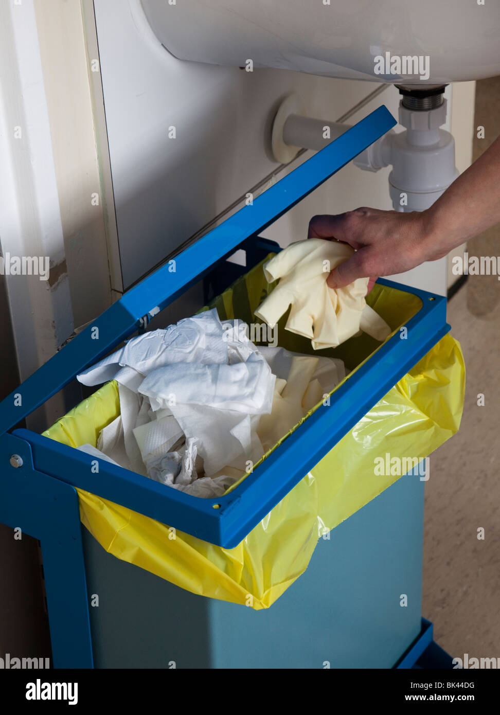Disposing of used surgical gloves in medical waste bin in hospital Wales UK Stock Photo