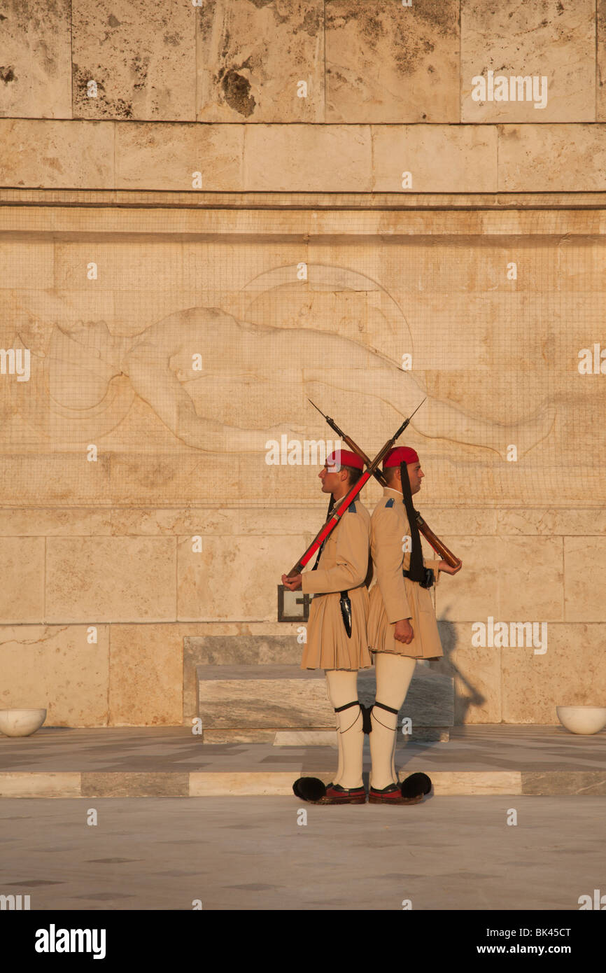 Evzones presidential guard defending the Tomb of the Unknown Soldier with sculpture of dying hoplite, Greek Parliament,  Athens Stock Photo