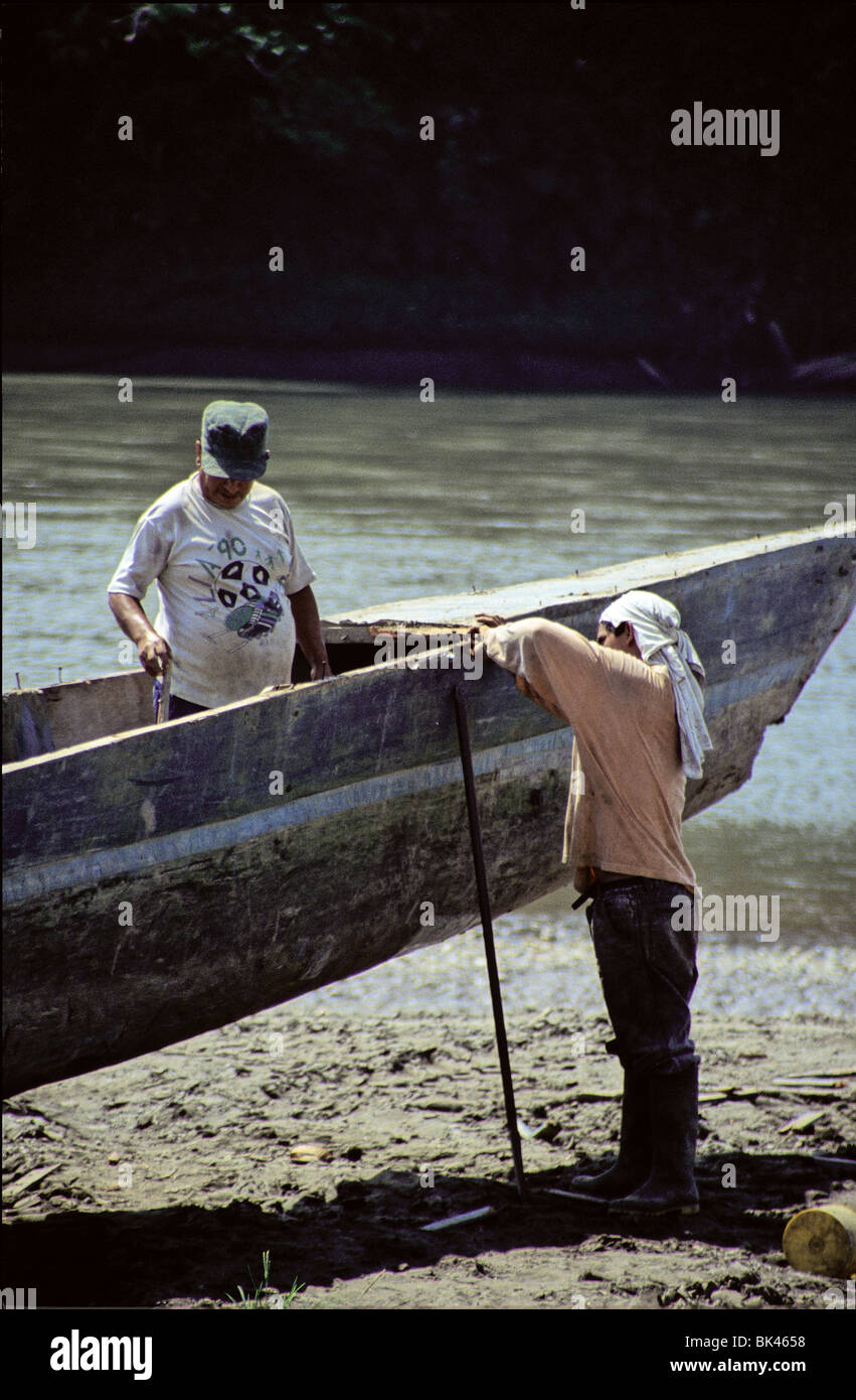 Two men working a homemade dugout boat along the Aguarico River, Ecuador Stock Photo