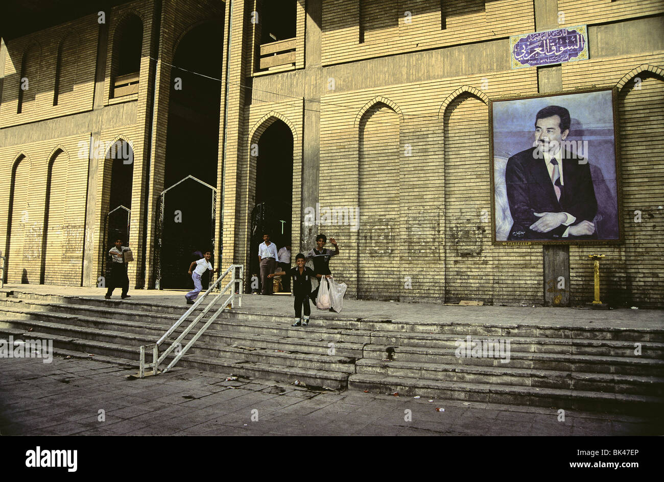 Young boys alongside a billboard painting of President Saddam Hussein, Baghdad, Iraq 1991 Stock Photo